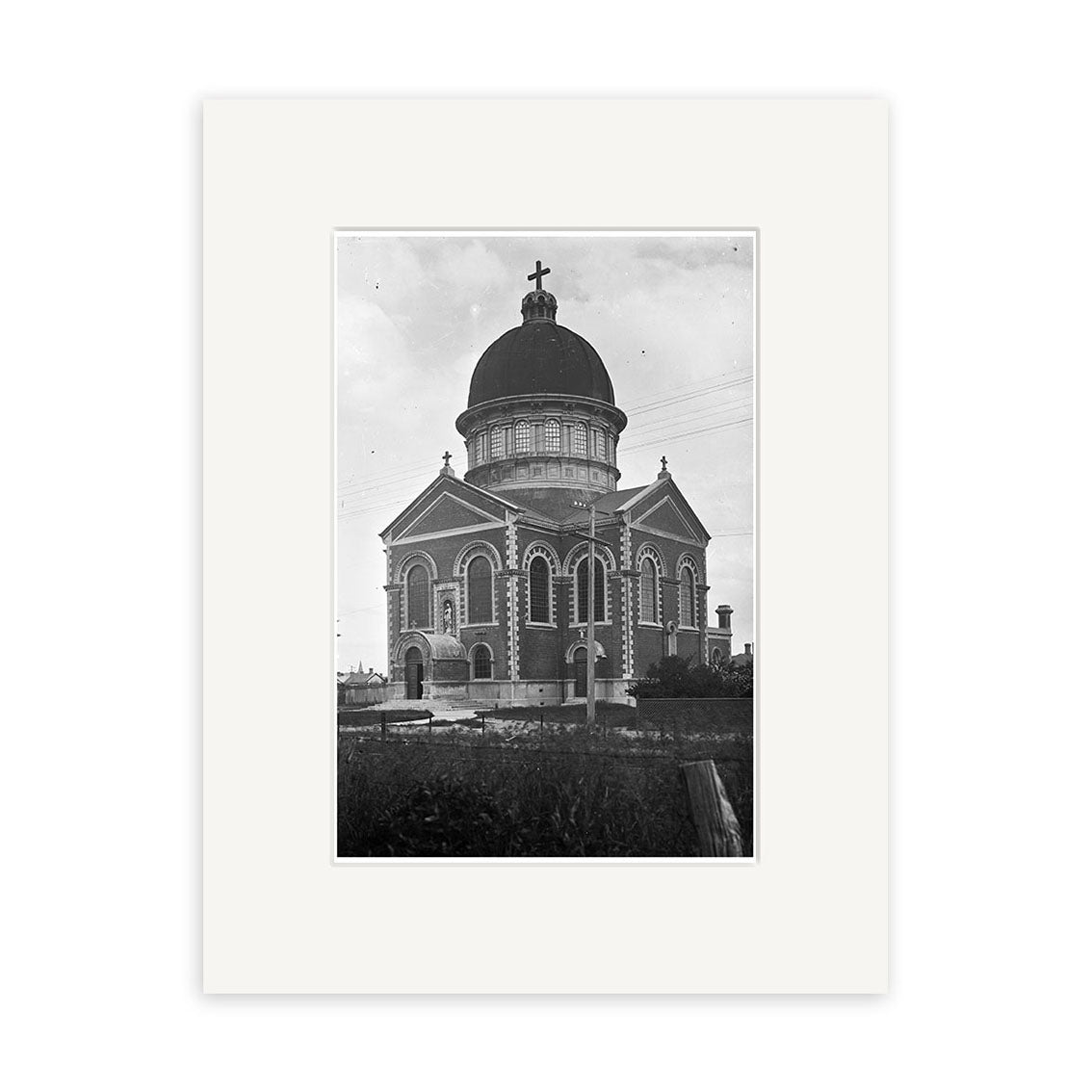 Archival black and white photographic print of Stmarys Basilica 1925 - HI136, showing the large brick church with domed roof, cross, arched windows, and ornate details. Surrounded by shrubbery under a cloudy sky, it captures New Zealands heritage.