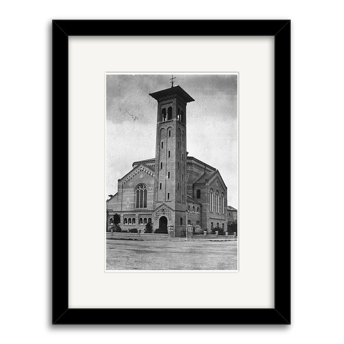 Black and white historical photographic print titled First Church 1924 - HI137 shows a large brick church with a tall bell tower, arched windows, and gabled roof, displayed in a black frame with a white mat.