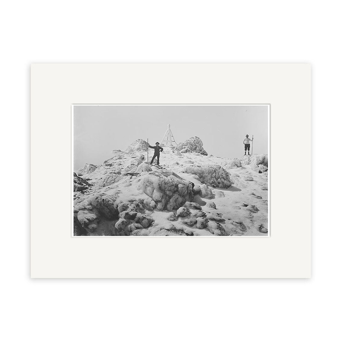 Mt Egmont 1911 - HI143: Black and white photo of two people on a snowy summit in New Zealand, with a wooden triangle structure behind them under an overcast sky. Historical Photographic Print on archival quality matte paper.