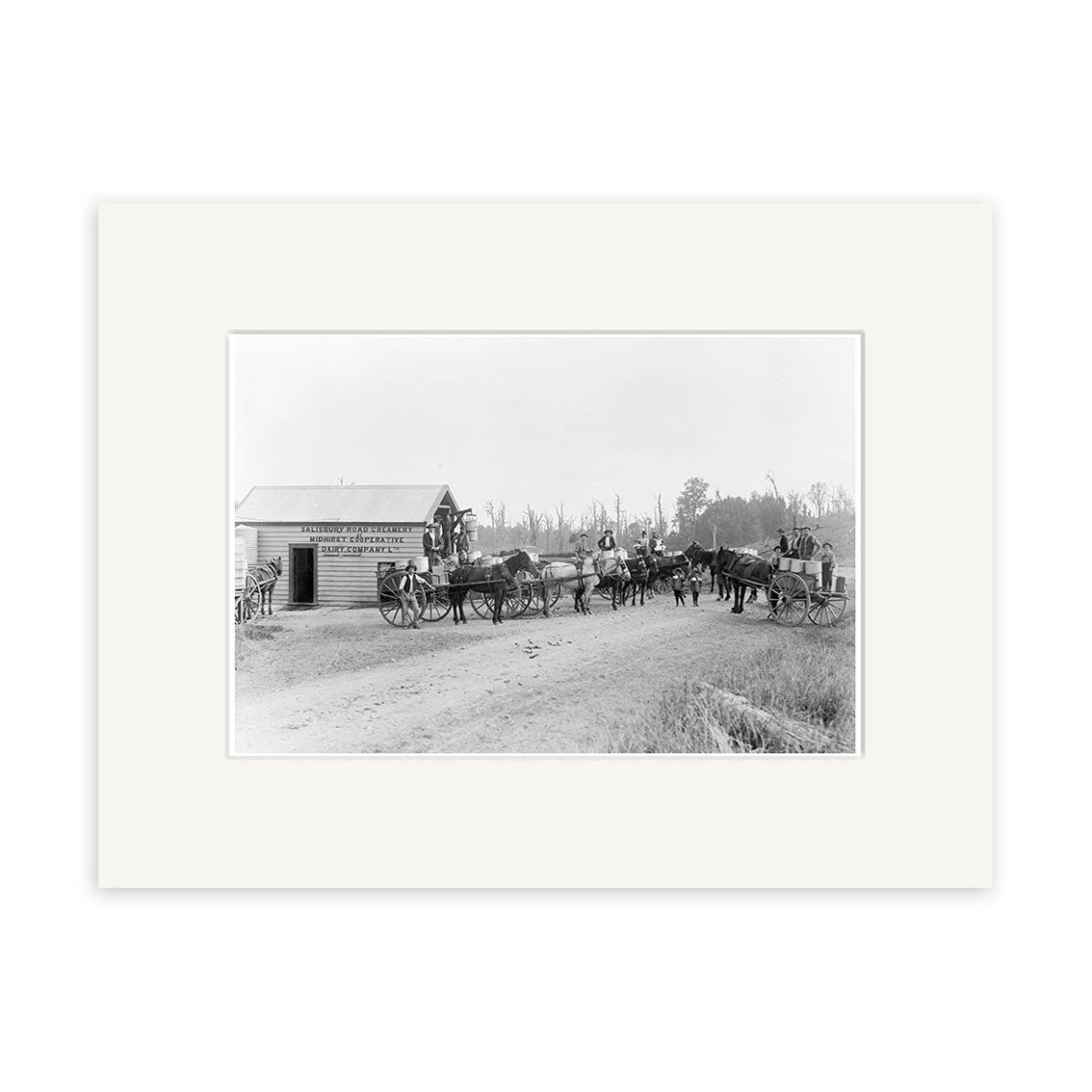 Archival black-and-white photographic print, Salisbury Rd 1900 - HI148, shows horse-drawn carriages stopped by a small wooden building, with people gathered on a dirt road and trees framing the scene in New Zealand.