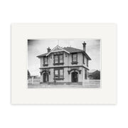 A historical 1910 print of Epsom Post Office (HI154), showing a two-story building, bicycle in front, picket fences, and houses behind. Printed on archival matte paper. A beautiful piece of New Zealand heritage.