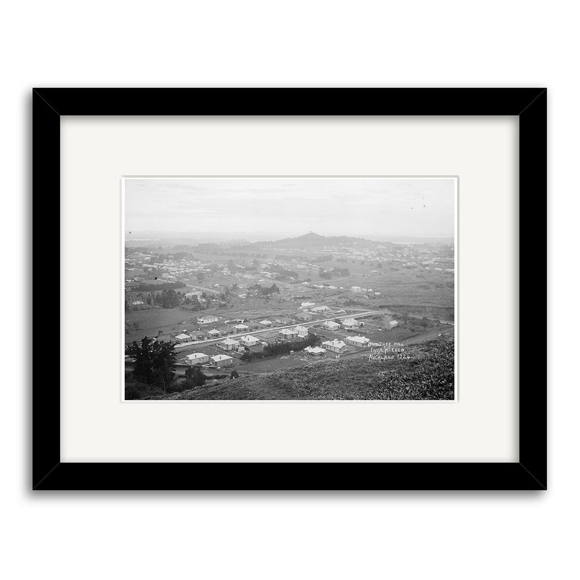 The Epsom 1910 - HI155 is a black and white historic photo print in a black frame, showing a distant view of Epsom, New Zealand in 1910 with scattered houses, open land, and hills under a clear sky.