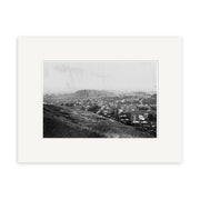 Archival quality black and white photo Epsom 1907 No.2 - HI159 shows a New Zealand town with houses and streets viewed from a hillside, larger hill and open land in the background, matted with a white border.
