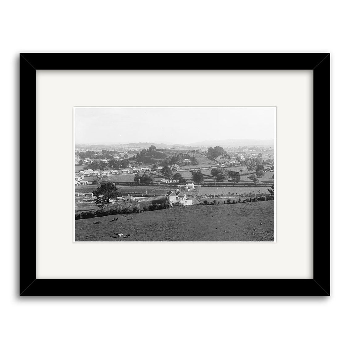 Epsom 1909 - HI160: Black and white historical print of a rural landscape with scattered houses, fields, and trees, viewed from above. Presented in a black frame with white mat on archival quality matte paper.