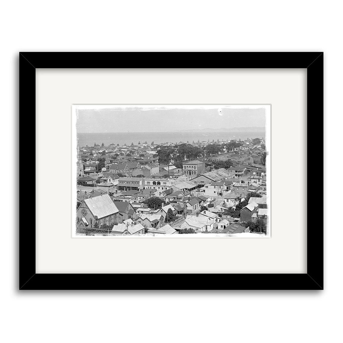 Archival black and white print, Napier 1924 - HI163, shows a densely built New Zealand town with houses, signage, horizon, and sky. Framed with a white mat and black frame for display.