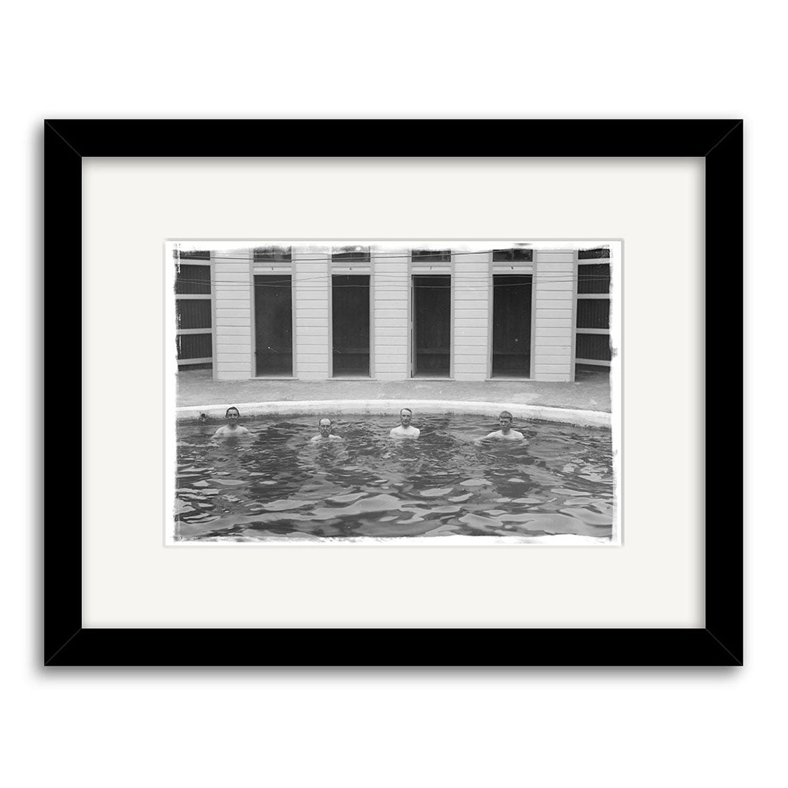 Baths Hanmer Springs 1900 - HI170: Black and white photo of four people in a pool with just their heads above water, building in background. Framed with white mat and black frame on archival quality matte paper.