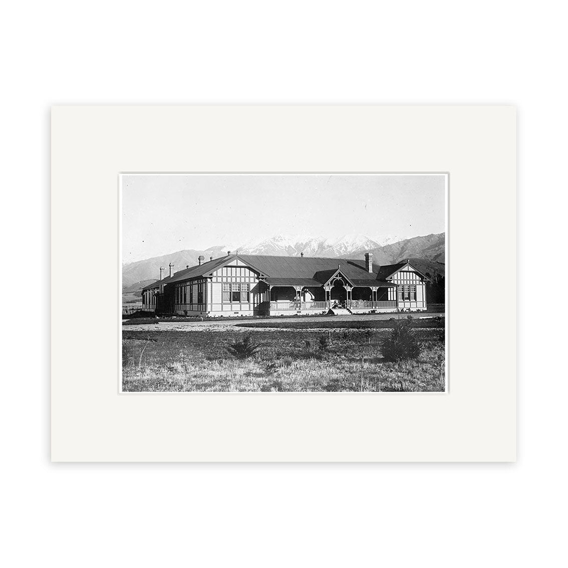 Archival black and white photo of Govt Sanatorium 1915 - HI171, a single-story building with a gabled roof and decorative trim, set in grassland with mountains visible in the background.