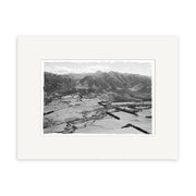 Black and white aerial photo titled Hanmer 1959 - HI172 shows fields, trees, a small town, and mountains. This historical print is framed with a white mat on archival-quality matte paper.