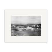 Black and white photo titled Jollies Pass hotel 1915 - HI173 shows a rural New Zealand landscape with a winding road, fenced fields, and distant hills. This archival quality print is presented with a white mat.