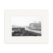 Cliff Street 1910 - HI176: Black and white historical print of a dirt road with a horse-drawn carriage and large two-story building in rural New Zealand hills, on archival quality matte paper for lasting detail.