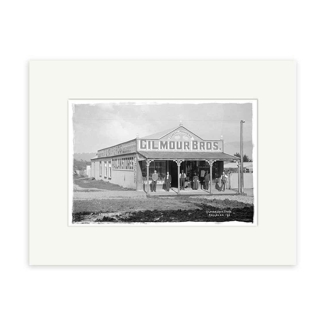 Black and white photo, Gilmour Bros Store 1910 - HI177, shows a group before the Gilmour Bros building in New Zealand, with clear signage for goods and services—historical detail in archival quality.