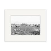 A black and white historical photographic print titled Green St Rangiora 1910 - HI178 on archival matte paper shows a muddy field, puddles, low buildings, fences, and a central structure in rural New Zealand.
