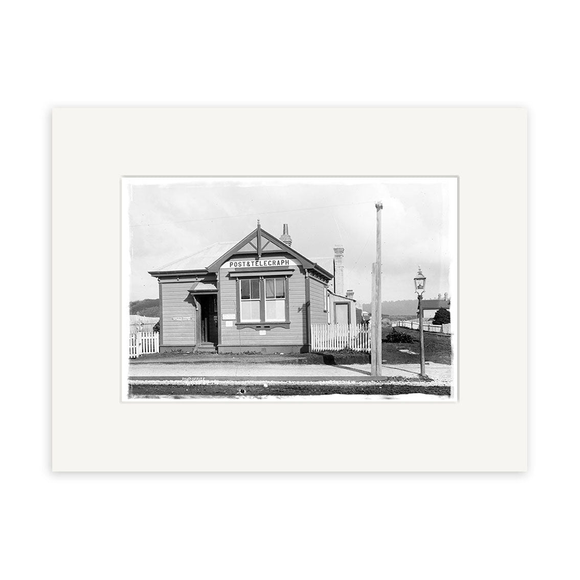 Post Office 1910 - HI182: Black and white historical photographic print of a small gabled-roof post office with Post Office sign, picket fence, lamp post, and street in front. Printed on matte archival-quality paper.