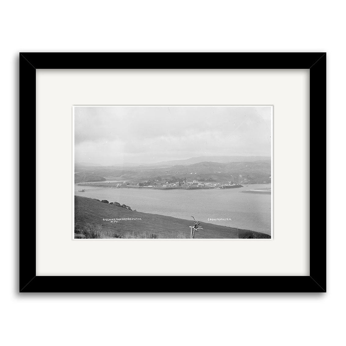 Framed black-and-white photo Raglan 1910 No.1 - HI184 shows a coastal town with water in front and hills behind, printed on archival matte paper with labels Gold Beach, Oregon and Crags Ferry, Oreg. on the image.