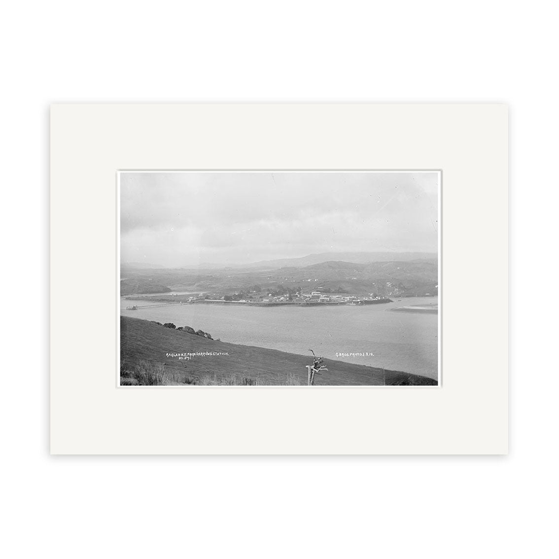 Raglan 1910 No.1 - HI184: Black-and-white historical photographic print of a coastal landscape with water, buildings, hills, and cloudy skies; labeled locations. Printed on archival quality matte paper.