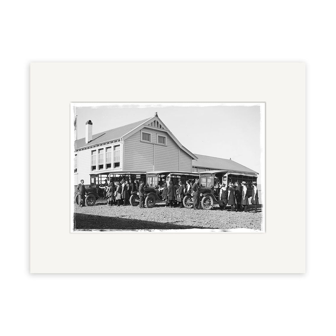 A black-and-white historical photographic print titled Piopio School Waitomo 1924 No.1 - HI191, showing people by early cars parked before a large two-story wooden building with a gabled roof in New Zealand.