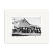 A black-and-white historical photographic print titled Piopio School Waitomo 1924 No.1 - HI191, showing people by early cars parked before a large two-story wooden building with a gabled roof in New Zealand.