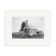 Black and white historical photographic print of St James Presbyterian Church 1915 (HI201), a small wooden church with a bell tower in New Zealand, surrounded by a fence, trees, other buildings, and featuring a sign and bench in front.