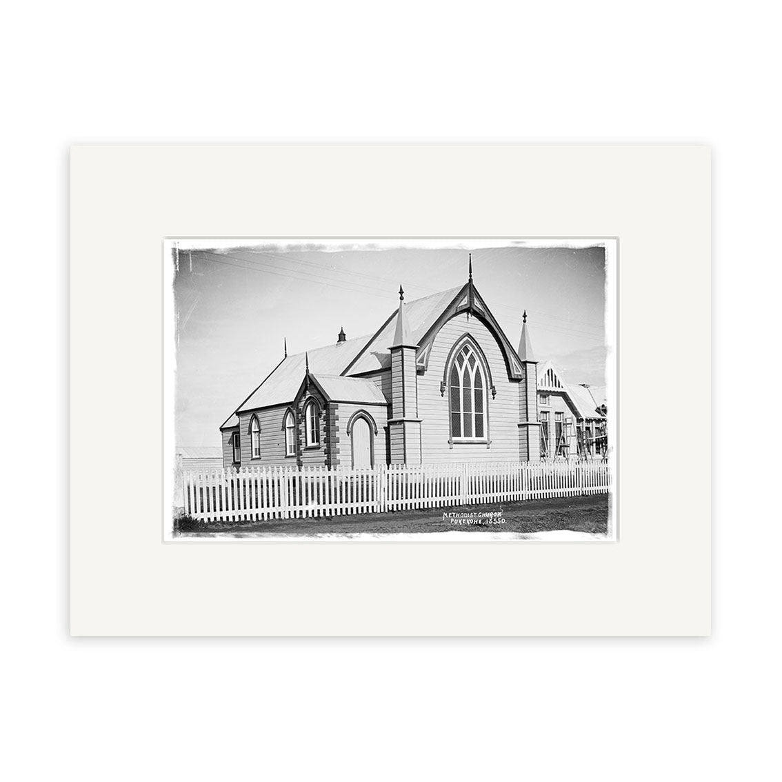 Archival quality Historical Photographic Print of Wesley Methodist Church 1918 – HI202. Black-and-white image shows steep gable roofs, pointed arches, tall windows, spires, and picket fence; print includes a white border.