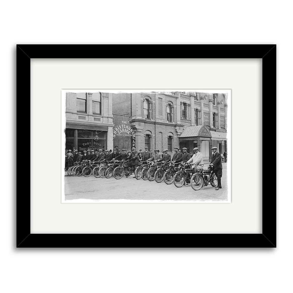 Motorcycle Group 1908 - HI207: Black and white photo of riders lined up on motorcycles before city buildings with onlookers. Historical Photographic Print, made in New Zealand on archival-quality matte paper.