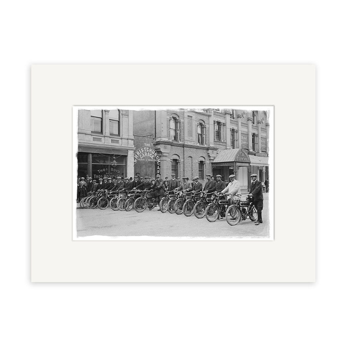 Black and white photo, Motorcycle Group 1908 - HI207, shows men on vintage motorcycles in front of The System Pharmacy. Printed as a Historical Photographic Print on archival matte paper. Several people observe this classic New Zealand scene.