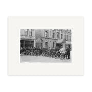 Black and white photo, Motorcycle Group 1908 - HI207, shows men on vintage motorcycles in front of The System Pharmacy. Printed as a Historical Photographic Print on archival matte paper. Several people observe this classic New Zealand scene.