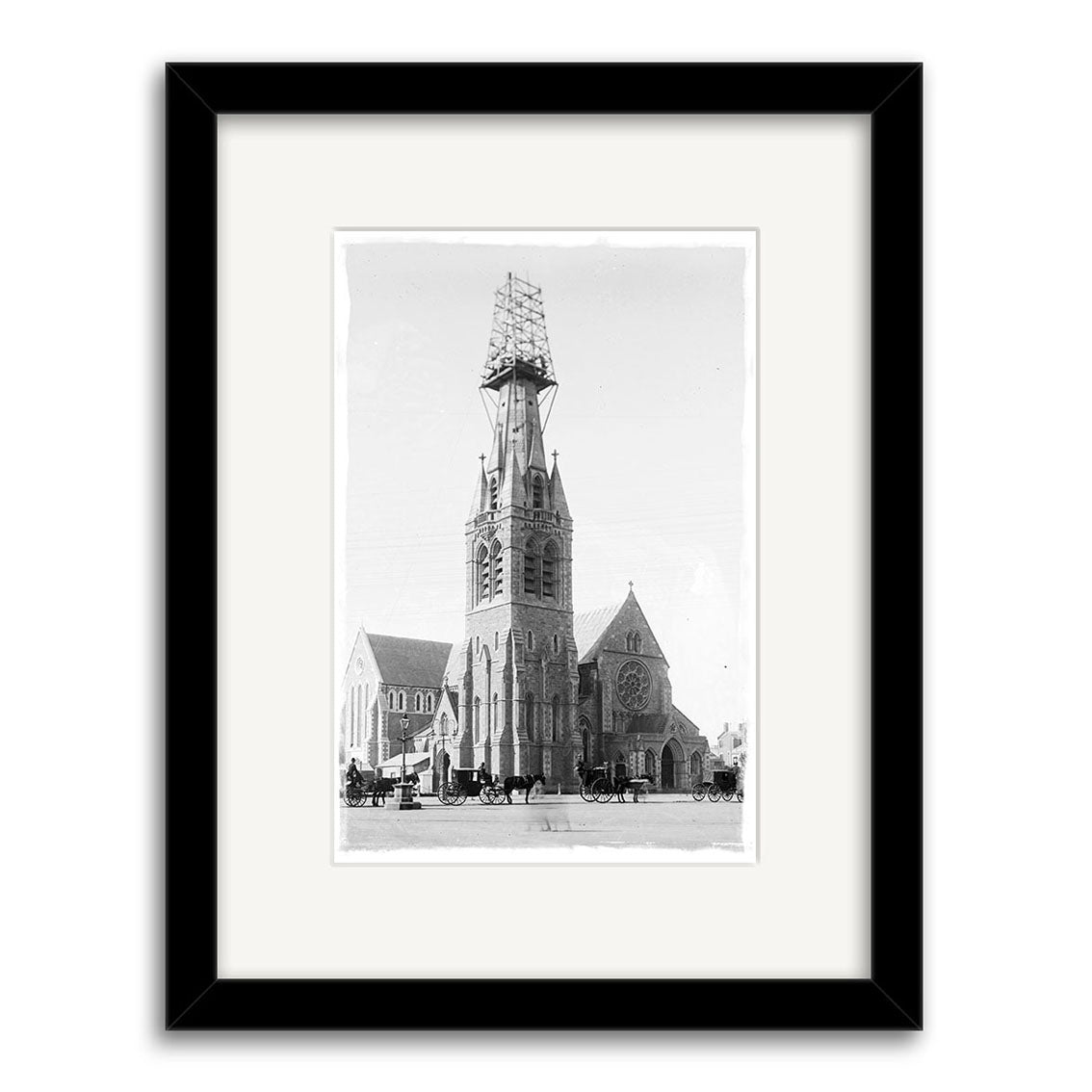 Cathedral Square 1903 - HI209: Historical black and white photo print of a large stone New Zealand church with its central tower under scaffolding and horse-drawn carriages out front, on archival quality matte paper.
