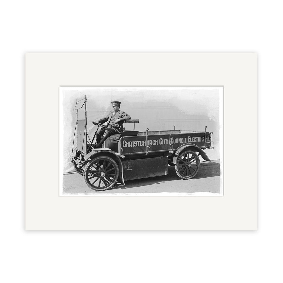 The City Council Electric 1920s - HI211 print captures a man in uniform on an early electric utility vehicle labeled Christchurch City Council Electric, with large wheels and an open cab, in New Zealand.