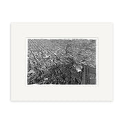 The Christchurch 1950 - HI213 is an archival quality black and white aerial photographic print. It shows a city grid, buildings, and a large tree-filled park in the foreground, matted with a white border.