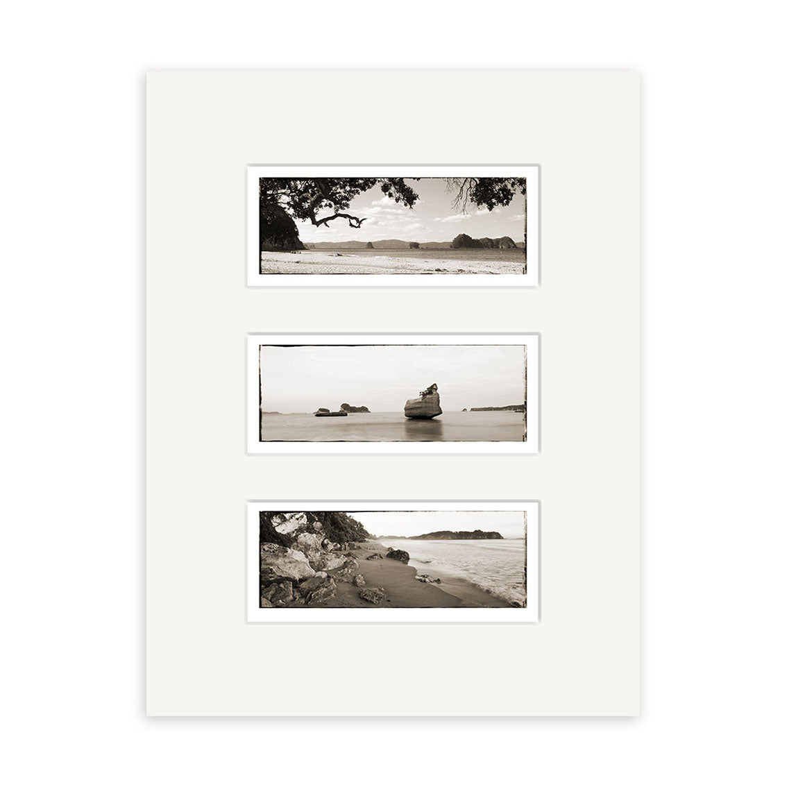 The Coromandel Triptych - RP124 features three black-and-white New Zealand coastal prints in a vertical white matte frame, each showcasing rocks, water, and landforms on archival quality matte paper.