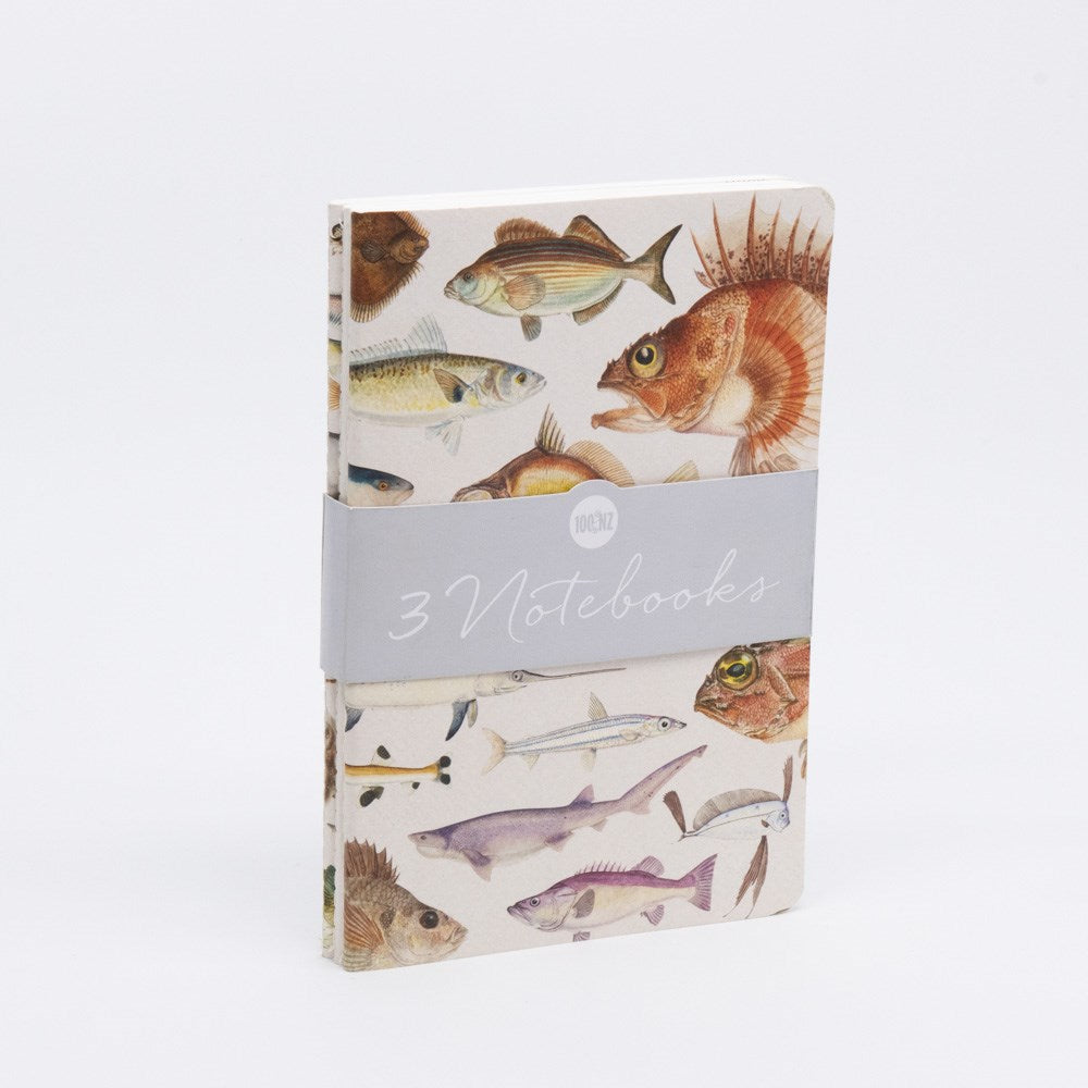 The Fishes of NZ Notebook Set includes three lined notebooks with illustrated fish covers, held together by a gray band labeled 3 Notebooks. Each features quality paper ideal for writing or sketching, shown on a plain white background.
