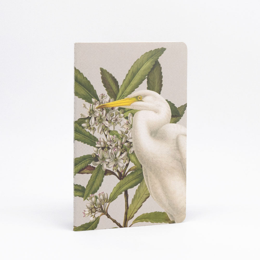 The Birds & Botanicals Notebook Set features quality paper and a cover illustration of a white egret among green leaves and white flowers on a light background, ensuring a smooth writing experience.