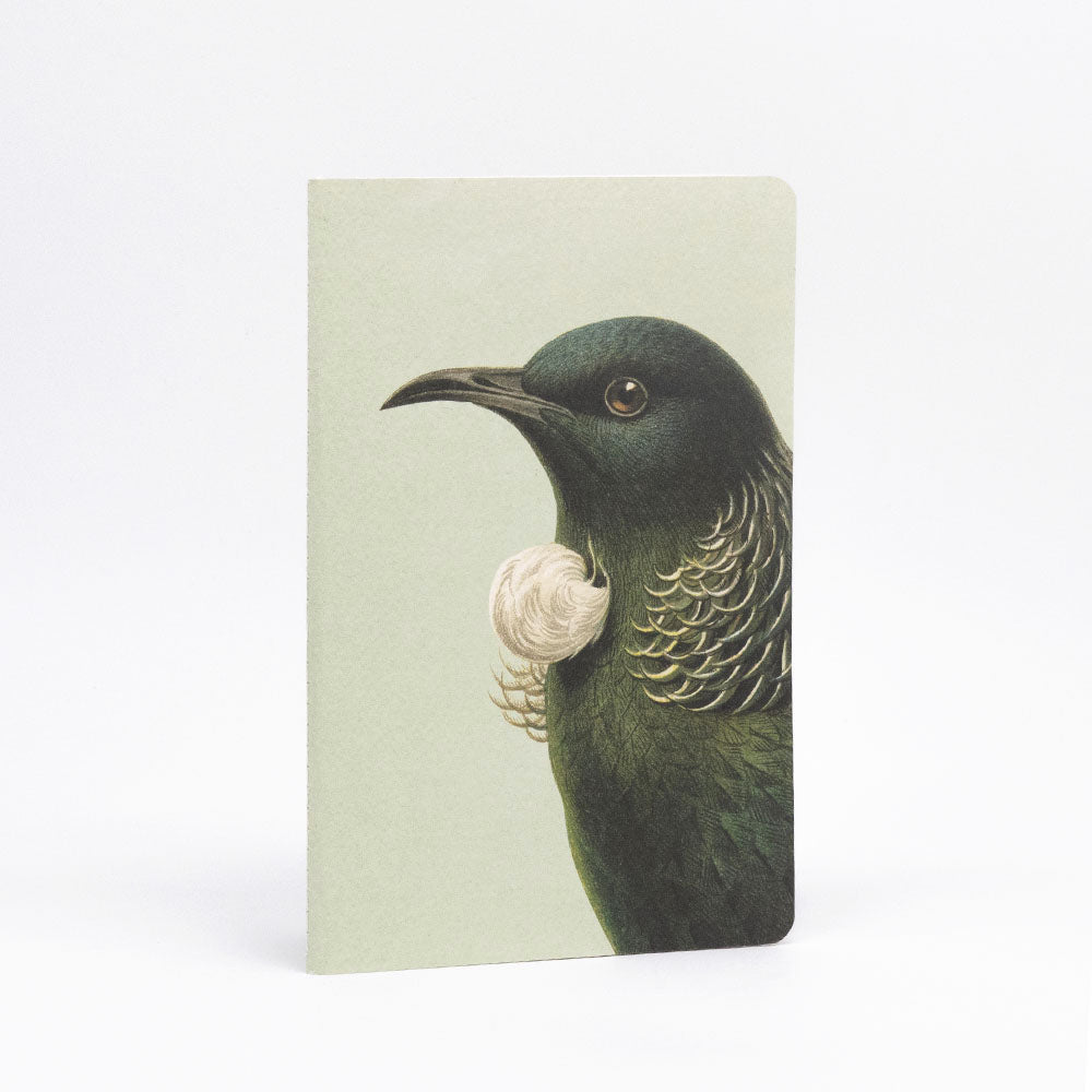 The Hushed Birds Notebook Set features a hand-stitched notebook with a left-facing tūī bird, dark green iridescent feathers, a white throat tuft, and a pale green background—crafted with quality paper for an exceptional writing experience.