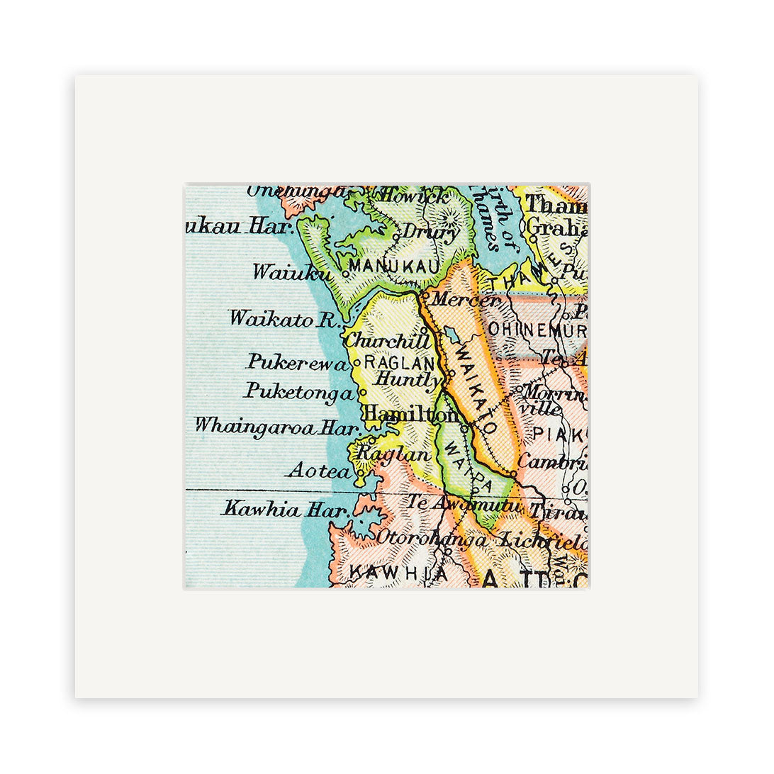 The Raglan Vintage Map Print is a close-up of a 19th-century lithograph showing New Zealands North Island, featuring place names like Hamilton, Raglan, Waikato, and Kawhia with colored boundaries and vintage typography.