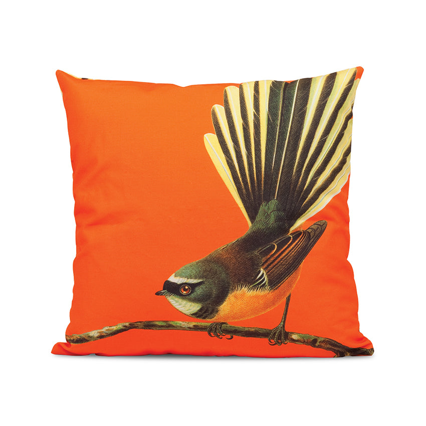 The Bright Fantail Cushion Cover from the Bright Birds Range is a square, orange polyester cover featuring a centered bird with a fan-shaped tail perched on a branch, set against a plain white background.