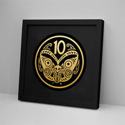 The 10 Cent Coin Foil Print is a black-framed art piece made in New Zealand, featuring a round gold stylized face with swirling patterns, the number 10 at the top, and J B initials at the bottom, set against a plain white wall.