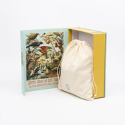 The NZ Native Bird Jigsaw Puzzle Box features a vintage bird illustration inside the book-style cover and holds a beige drawstring bag—an ideal gift for jigsaw puzzle and bird lovers. Set against a white background.
