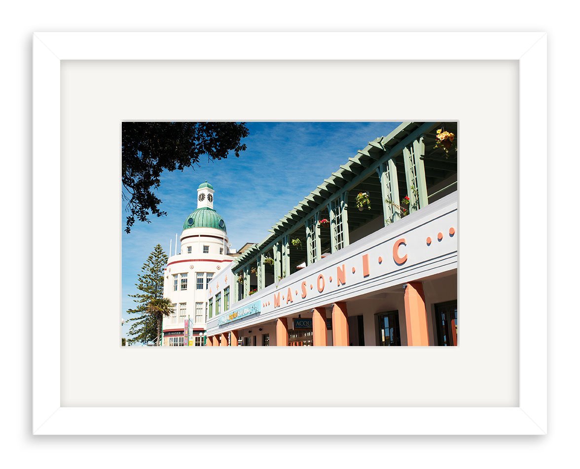The Masonic - RP146 is a framed photo of New Zealands Art Deco Masonic building, featuring green columns, orange lettering, and a domed tower against a blue sky. Printed on archival quality matte paper for lasting impact.