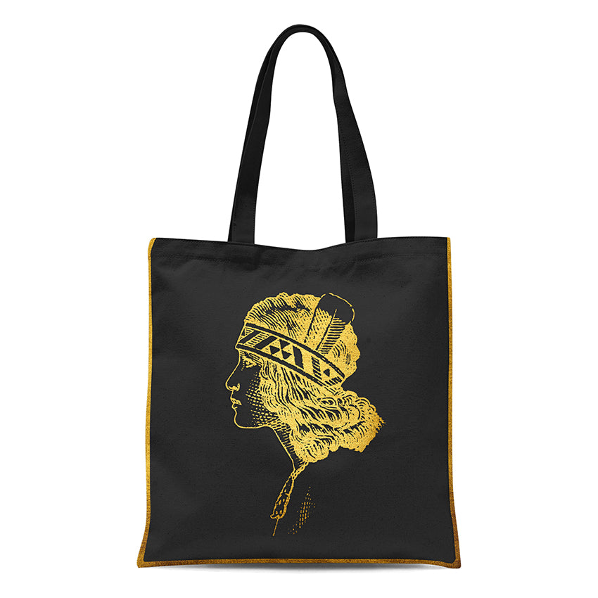 The Gold Foil Wahine Tote Bag features a bold yellow profile of a woman with a geometric feathered headband on black, accented with yellow trim and proudly designed in New Zealand.