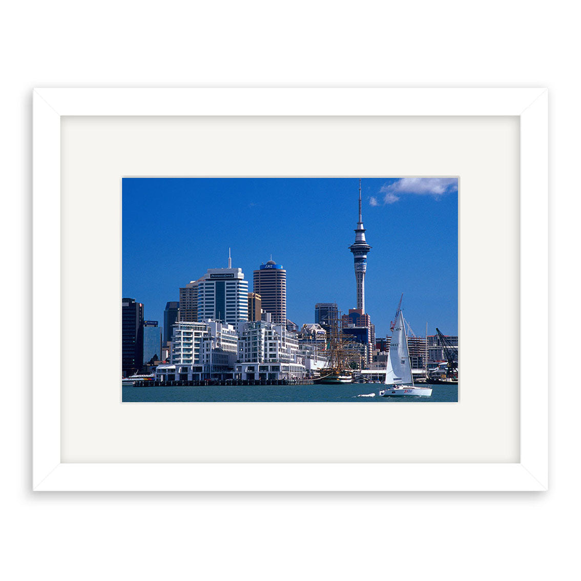 Auckland City - RP005: A framed photo of Auckland’s skyline with modern buildings, tall tower, sailboat in the foreground, and blue sky—printed on archival quality paper for lasting beauty.