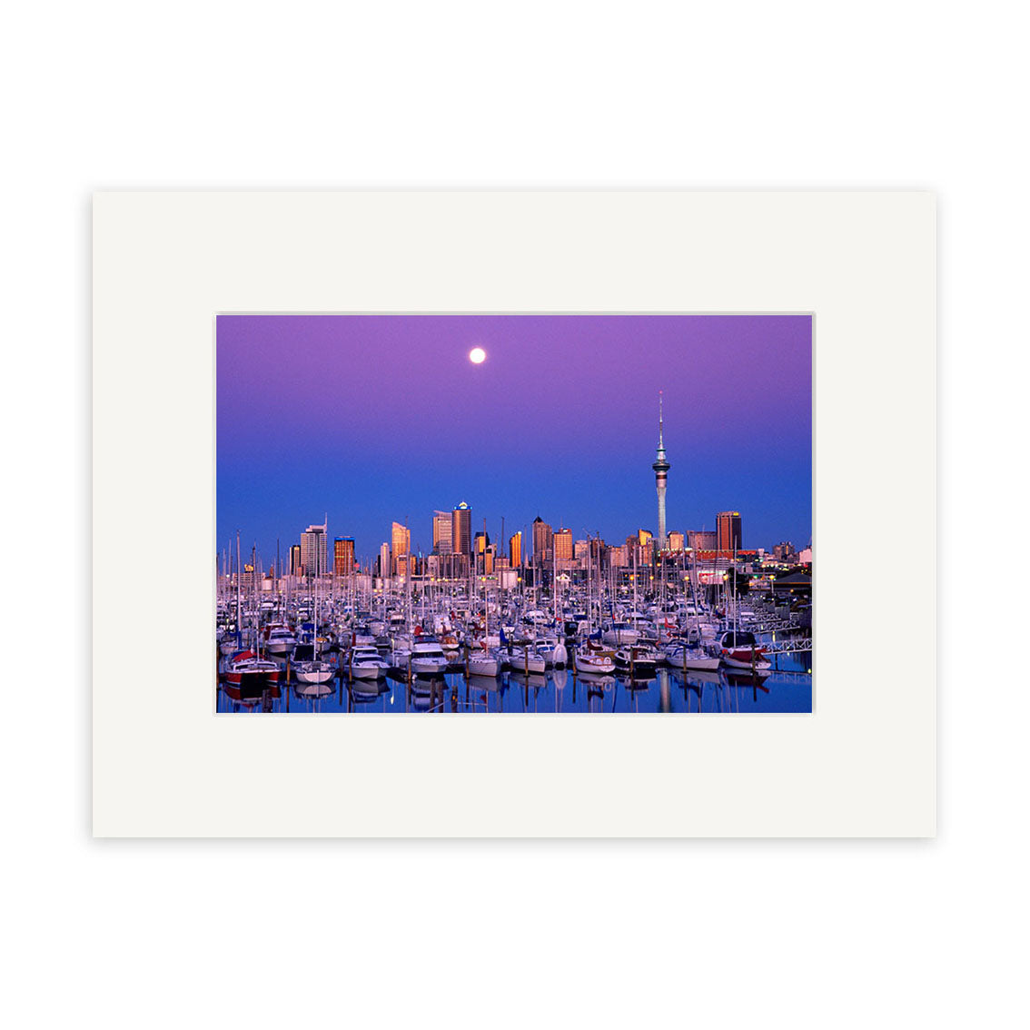 Twilight Boats - RP009: A marina full of boats under a purple sky, city skyline, tall tower, and rising full moon. This captivating New Zealand scene is available as a photographic print on archival quality paper with a white mat frame.