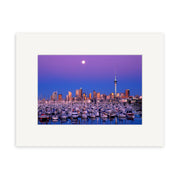 Twilight Boats - RP009: A marina full of boats under a purple sky, city skyline, tall tower, and rising full moon. This captivating New Zealand scene is available as a photographic print on archival quality paper with a white mat frame.