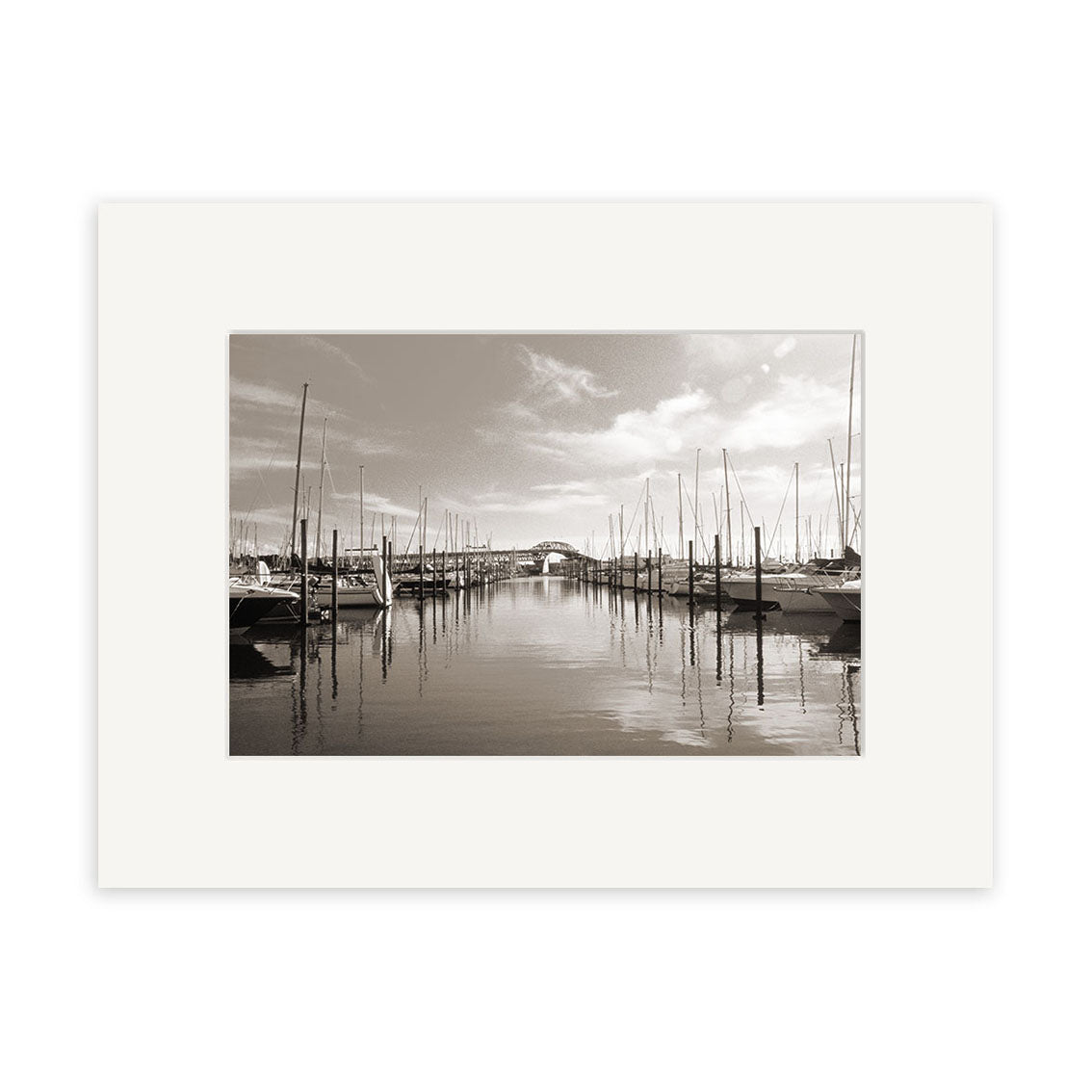 Westhaven Marina - RP020 is a black and white photo of a New Zealand marina with docked sailboats and calm water, framed by a white mat and printed on archival quality matte paper for timeless appeal.