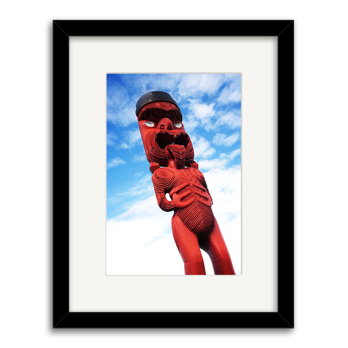The Maori Statue - RP041 features a framed photo of an intricate red Maori wood carving set against a blue sky, printed on archival paper to highlight the carving’s detailed patterns and expressive craftsmanship.