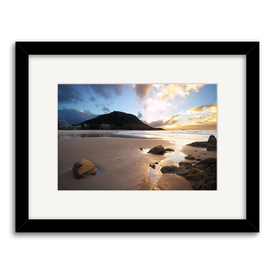 Framed photographic print titled Mt Maunganui - RP043, featuring a sandy New Zealand beach at sunset with rocks, reflective water, distant mountains, and buildings—captured on archival quality matte paper.