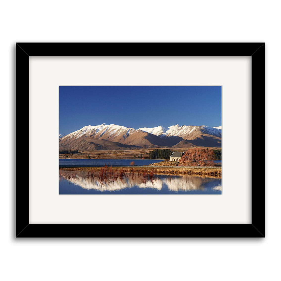 The Lake Tekapo - RP047 framed photographic print showcases a New Zealand landscape with a small house by the lake, snow-capped mountains, and blue sky reflected in the water, printed on archival quality matte paper.