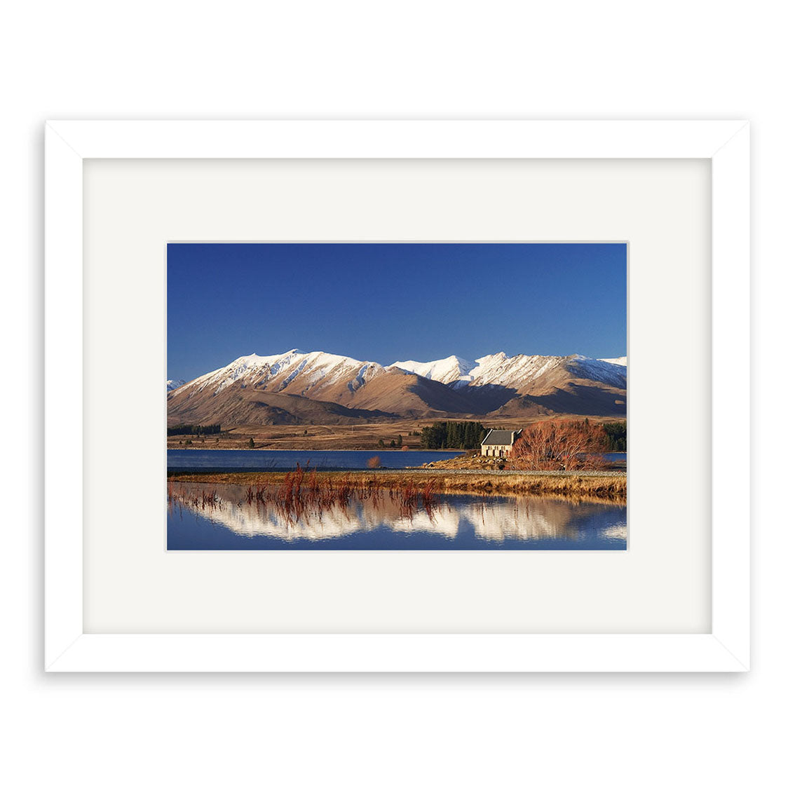 A framed photo of Lake Tekapo (RP047) in New Zealand, featuring a small house by the lake with snow-capped mountains and a clear blue sky, printed on archival quality matte paper.