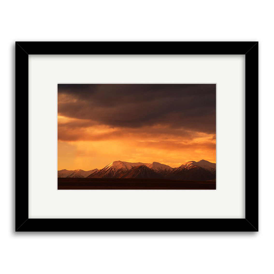 Southern Alps - RP049: A framed photographic print of New Zealand’s snow-capped mountains at sunset, with dramatic skies. Printed on archival matte paper and set in a black frame with a white mat border.