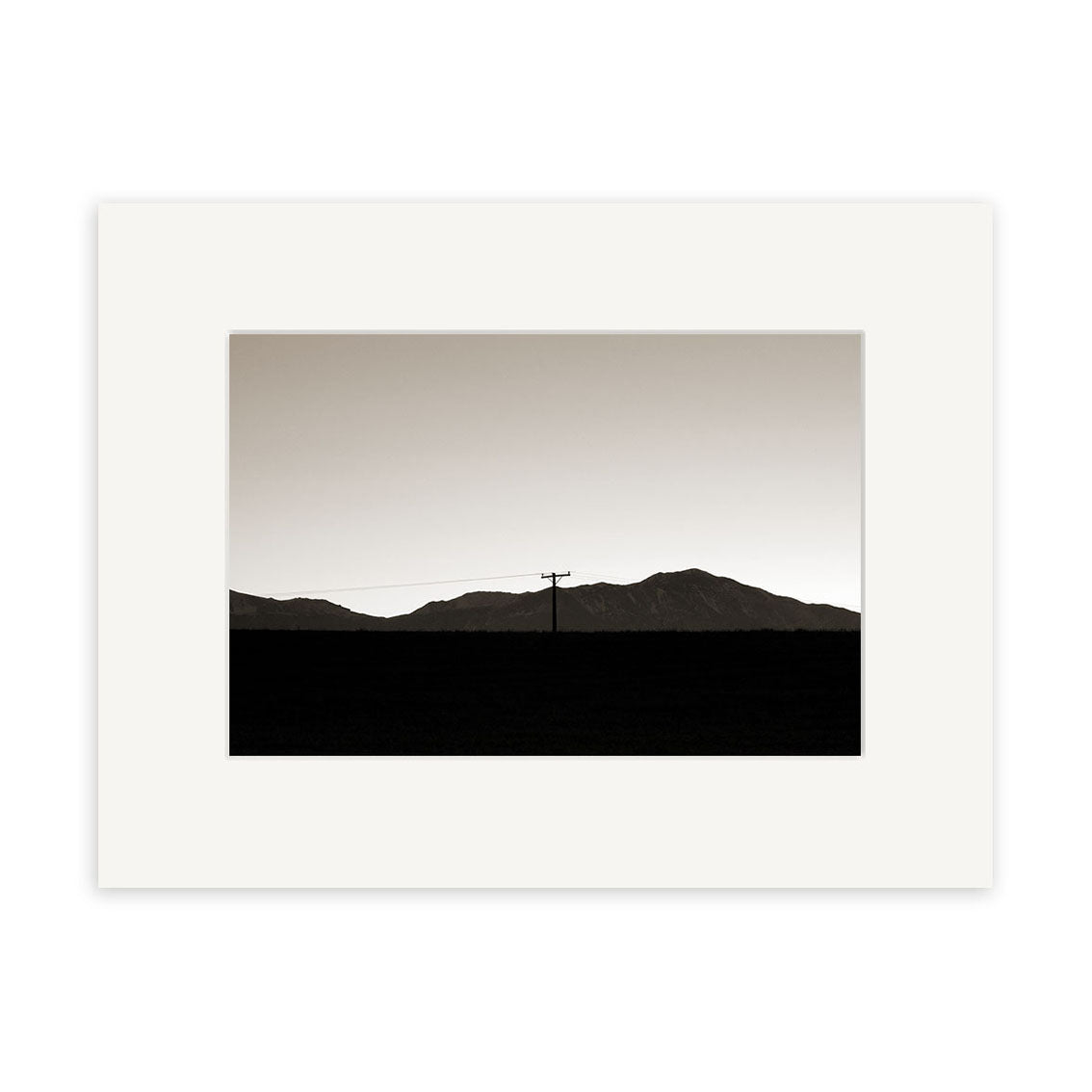 Canterbury Dusk - RP050 is a black and white photo featuring a telephone pole and power line before distant New Zealand mountains, presented as archival quality prints with a simple white matte border.