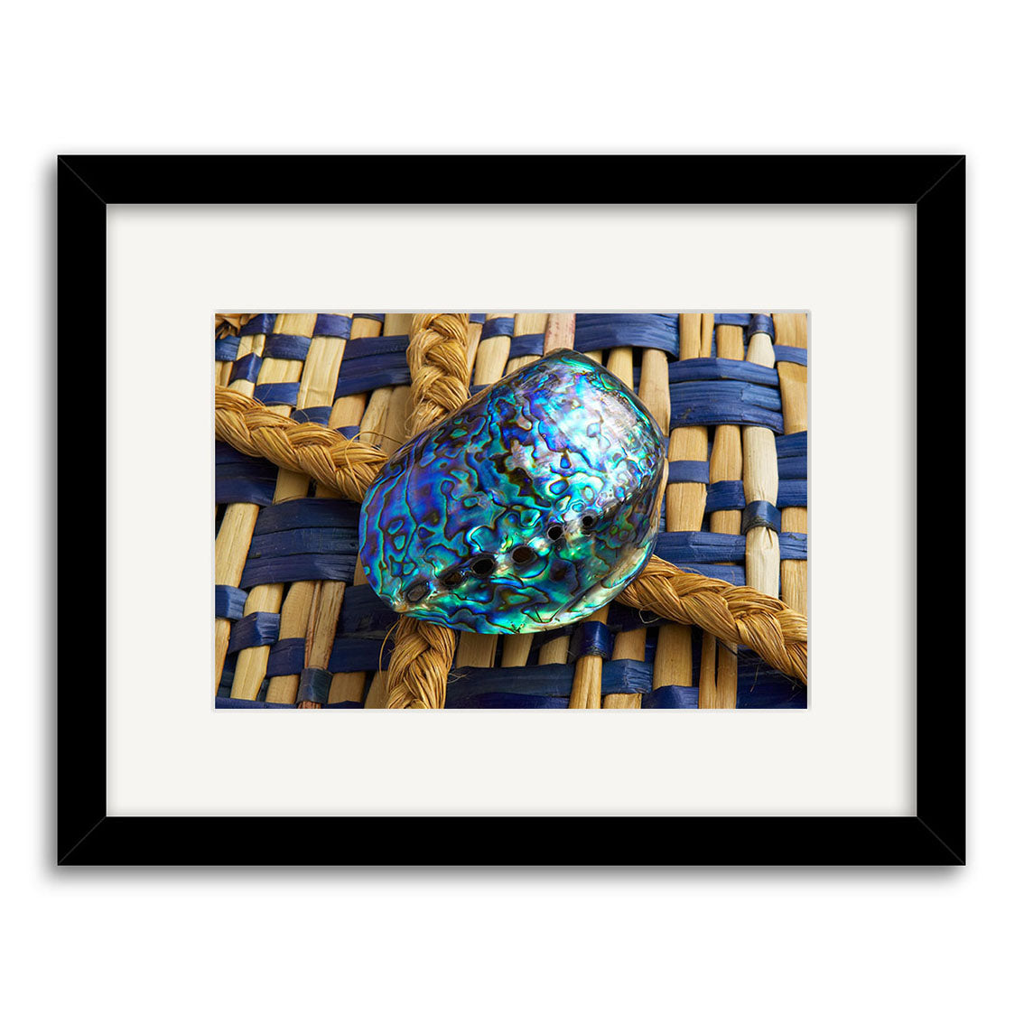 The Paua Shell - RP085 is a framed photo of a shiny, multicolored abalone shell on a woven blue and tan mat, printed on archival matte paper and displayed against a white background.